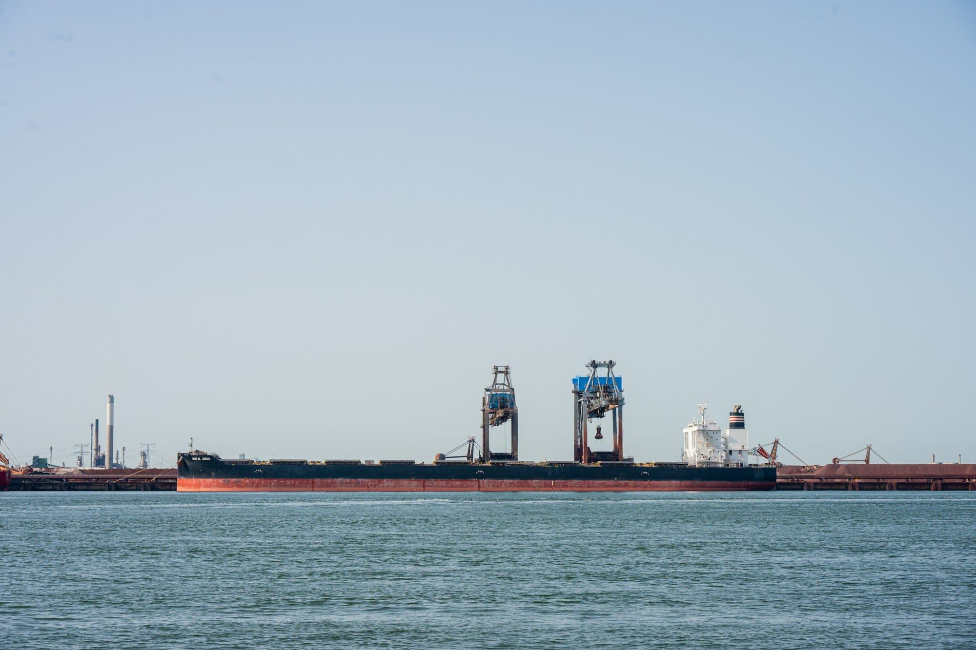A bulk carrier with its own cranes lying in harbour
